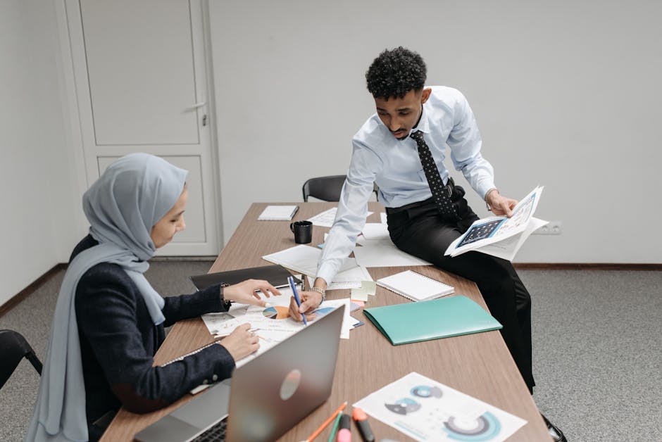 Colleagues discussing documents in a modern office meeting room.